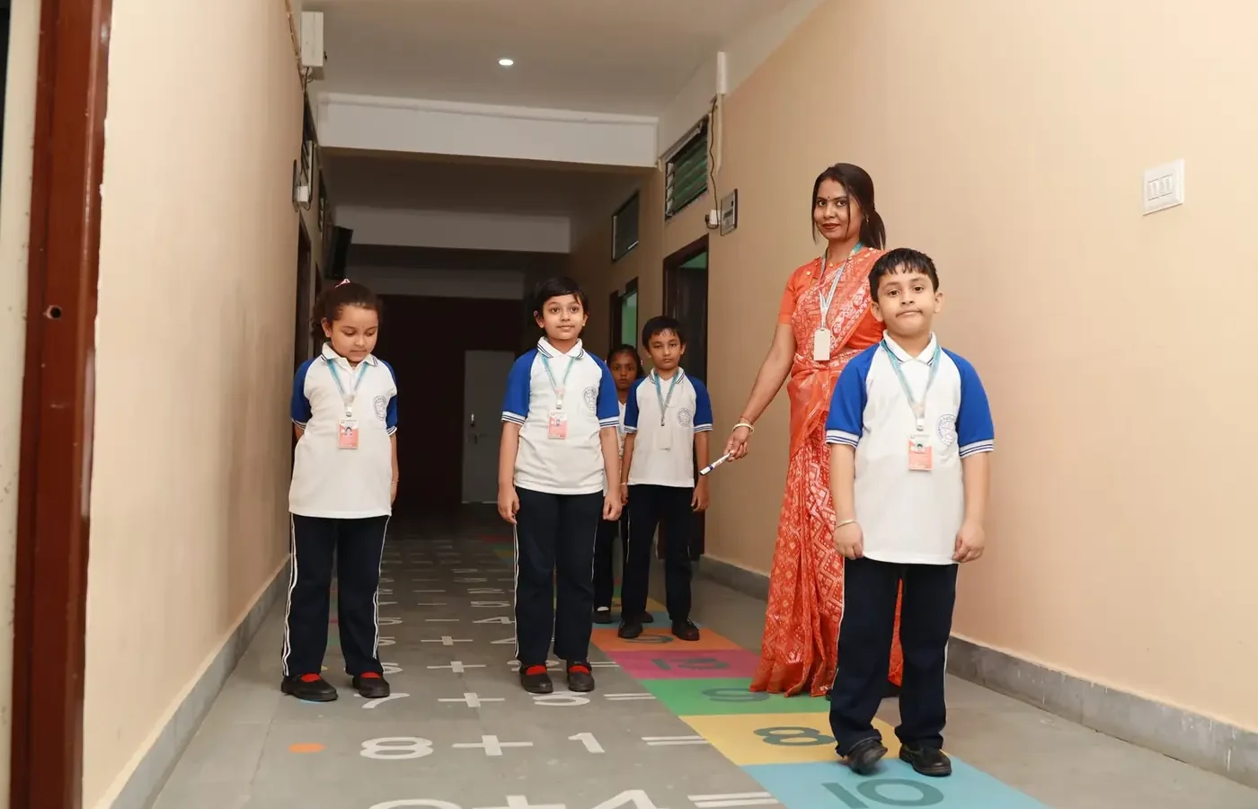 A teacher guiding small children over the number game painted on the corridor floor