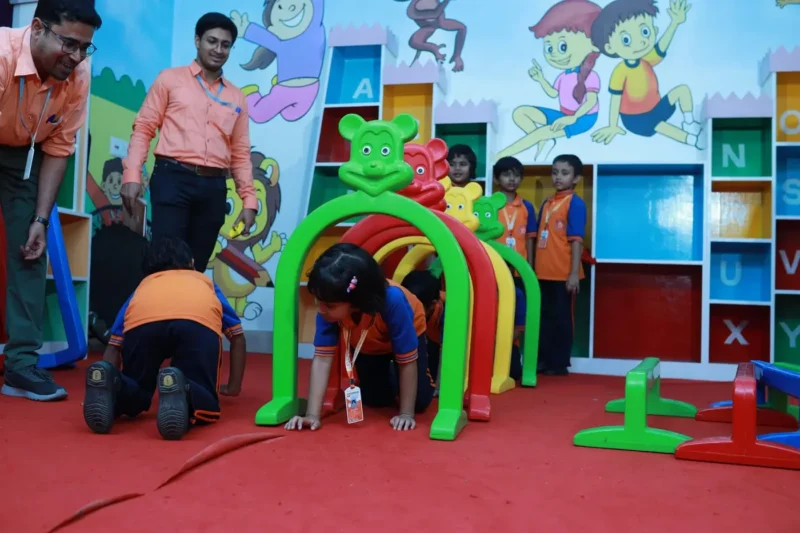 Children crawling through a soft-play tunnel in the indoor activity room